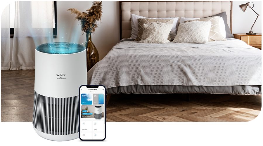 WINIX air purifier with a smartphone in front of a bed